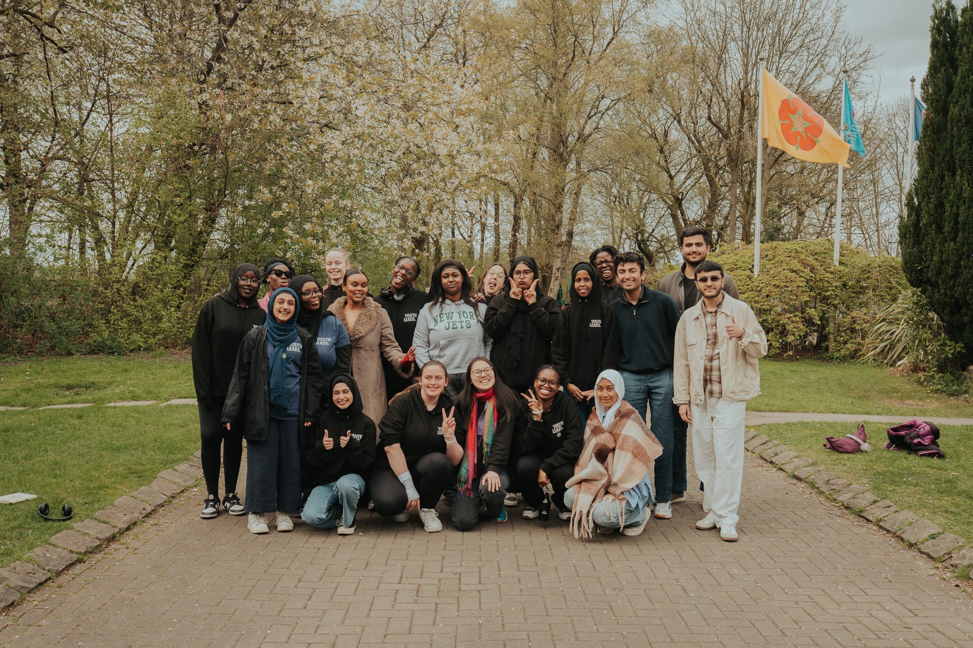 A group of young people pose for the camera in front of blossoming trees.