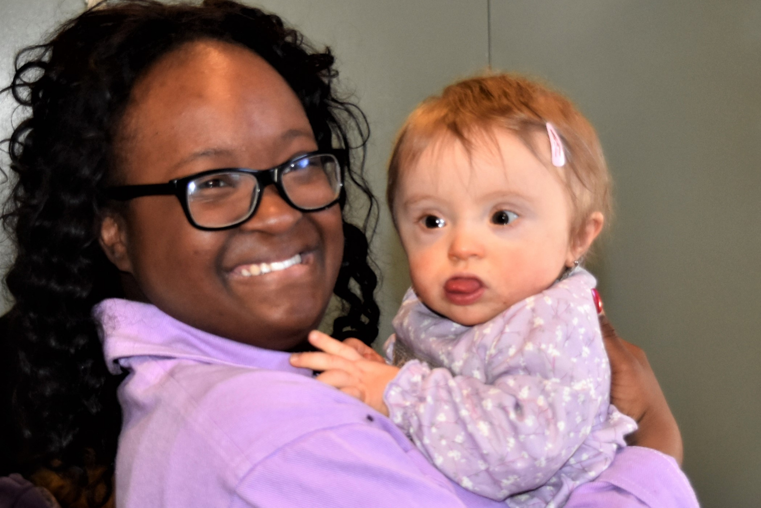 A black woman holding a white toddler