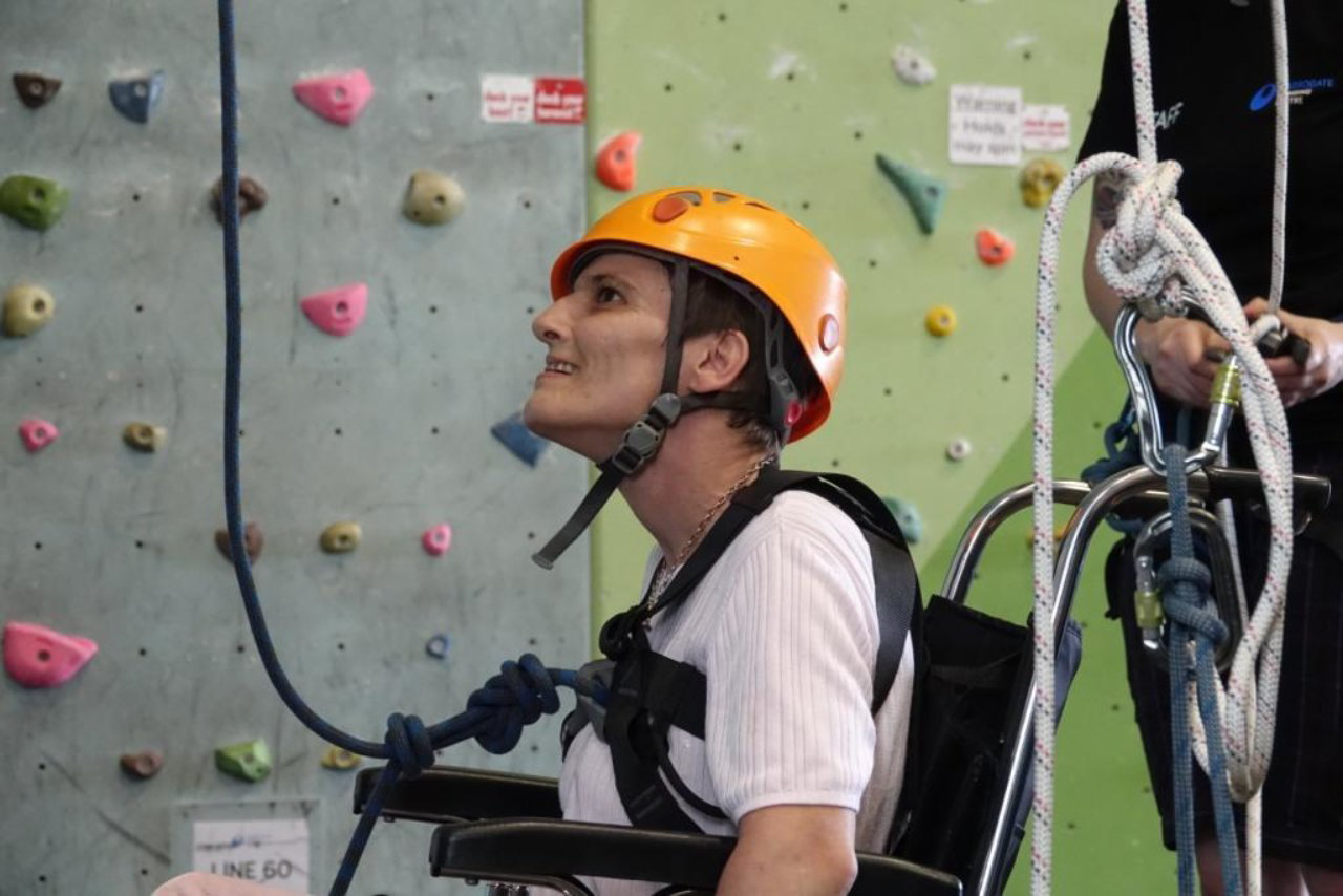 A disabled person in a wheelchair about to be hoisted up a climbing wall