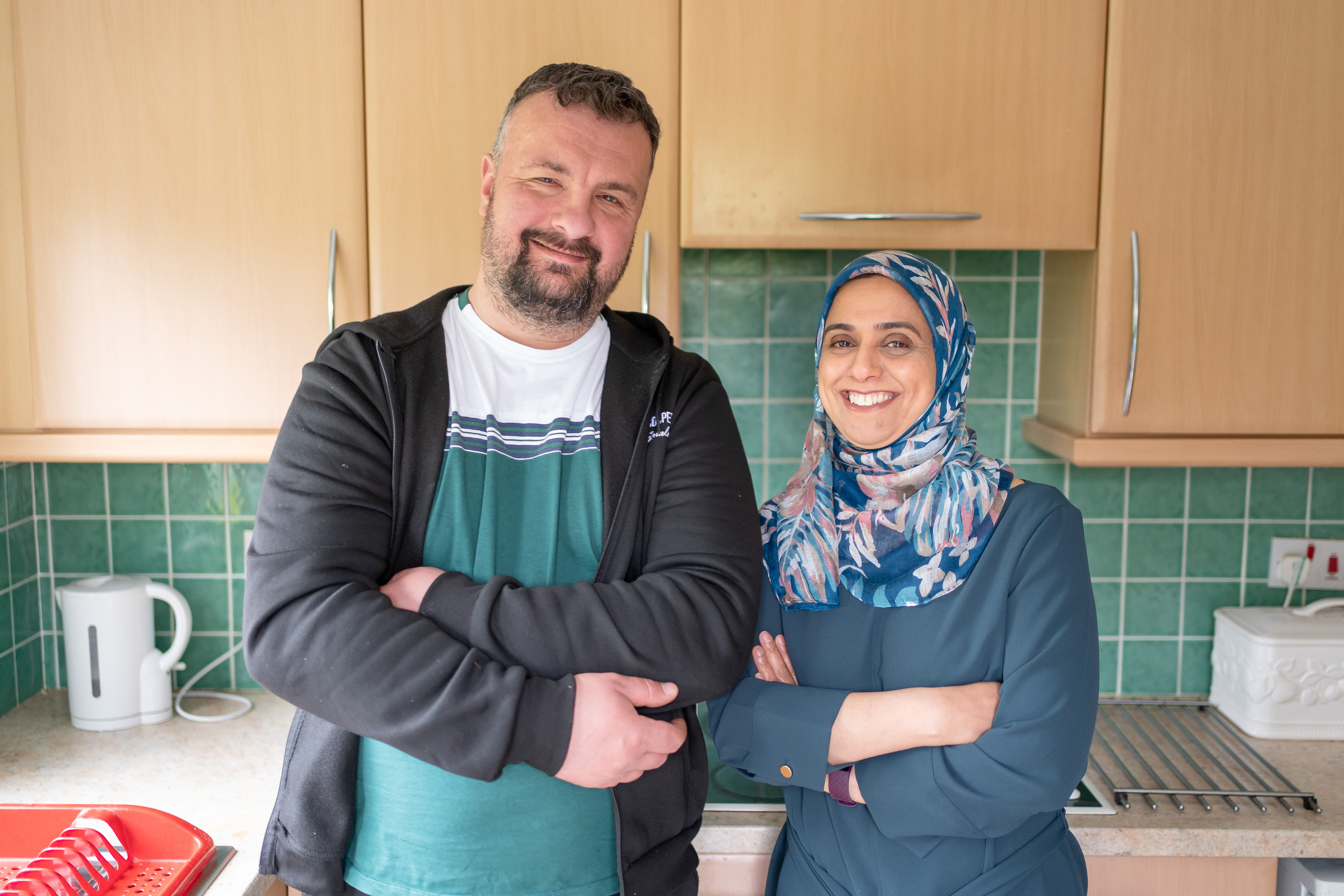 Two people standing in a kitchen looking at the camera and smiling