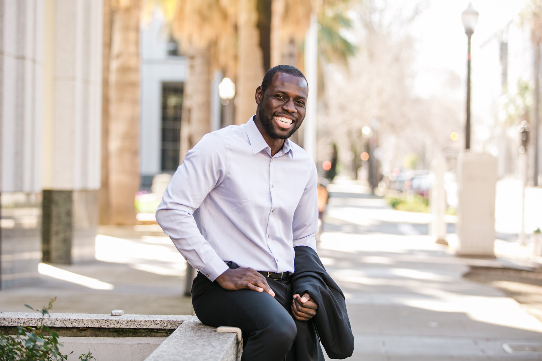 A black man sitting on a wall