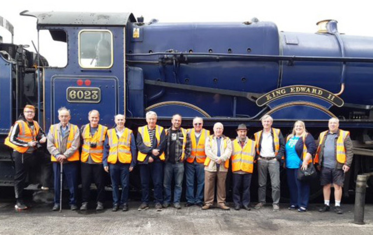 A group of people in front of a steam train