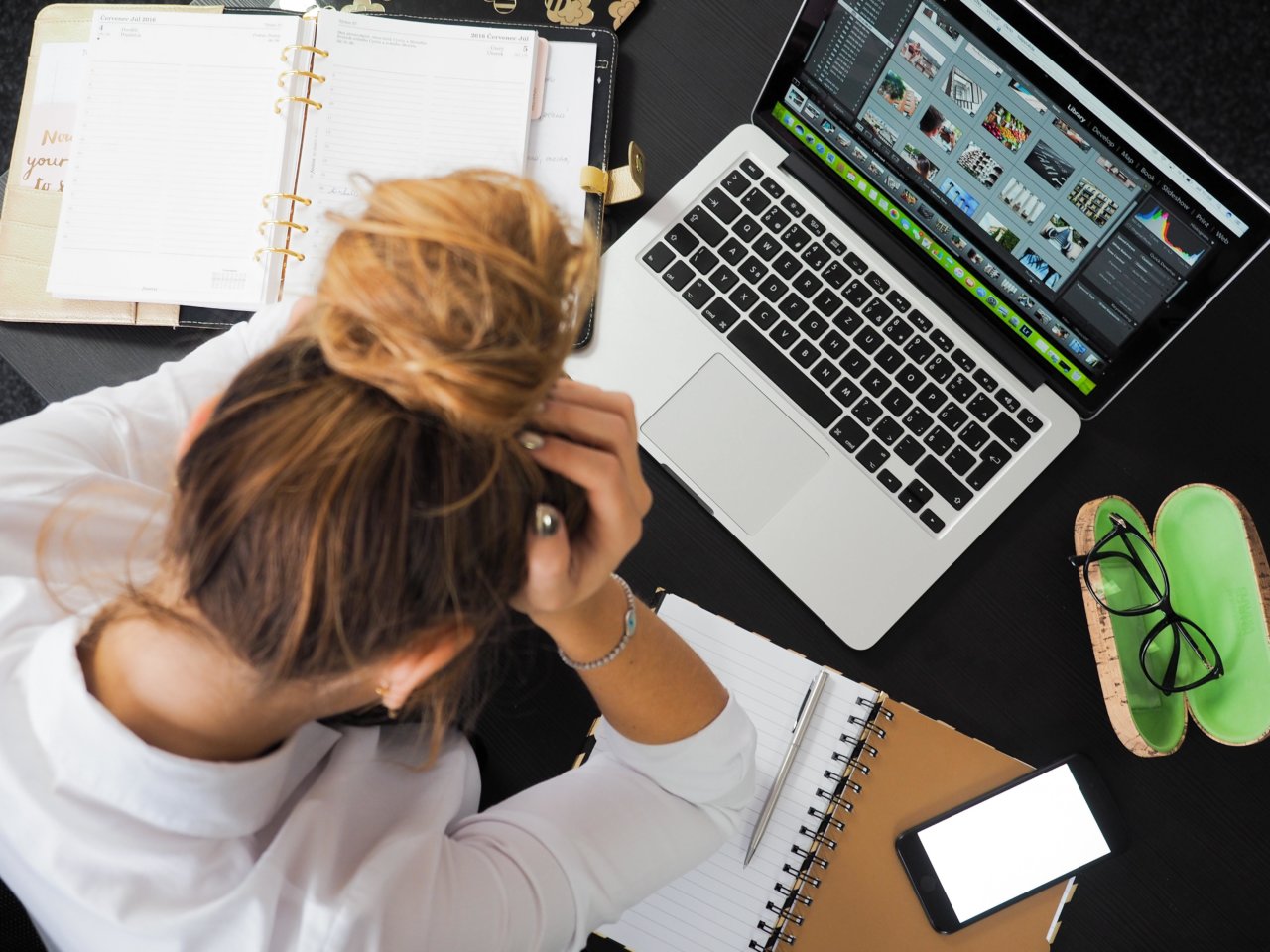 A person holding their head in front of a desk